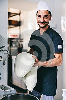 Italian chef pizzaiolo preparing pizza dough in restaurant kitchen