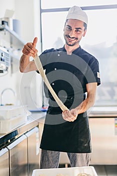 Italian chef pizzaiolo preparing pizza dough in restaurant kitchen