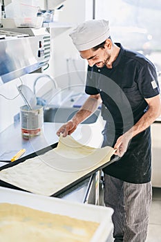 Italian chef pizzaiolo preparing pizza dough in restaurant kitchen