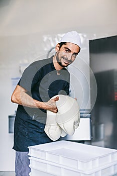 Italian chef pizzaiolo preparing pizza dough in restaurant kitchen