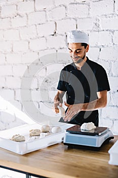 Italian chef pizzaiolo preparing pizza dough in restaurant kitchen