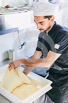 Italian chef pizzaiolo preparing pizza dough in restaurant kitchen