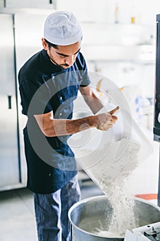 Italian chef pizzaiolo preparing pizza flour in restaurant kitchen