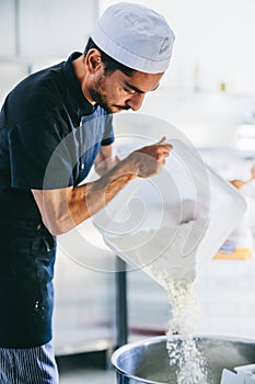 Italian chef pizzaiolo preparing pizza flour in restaurant kitchen