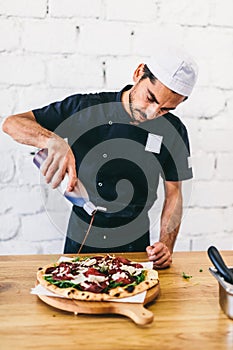 Italian chef pizzaiolo putting balsamic vinegar on pizza