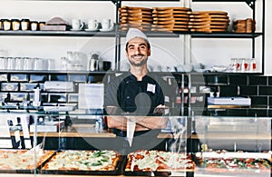 Italian chef or pizzaiolo with sicilian pizza in restaurant