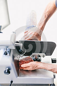 Italian chef slicing ham for pizza in restaurant kitchen