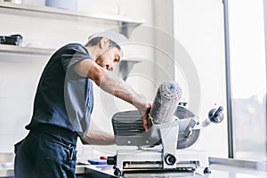 Italian chef slicing ham for pizza in restaurant kitchen