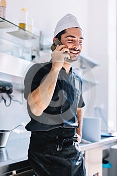 Italian chef talking on mobile phone in restaurant kitchen