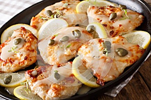 Italian chicken piccata with sauce, lemon and capers close-up. H