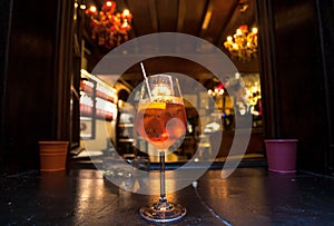 Italian cocktail Aperol spritz on table of historical bar. Old city restaurant with popular drinks at evening time