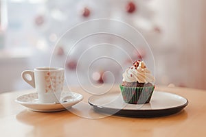 Italian coffee Cup and cupcake on the table near the Christmas tree with white bokeh