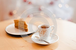 Italian coffee Cup and honey cake on the table near the Christmas tree with white bokeh