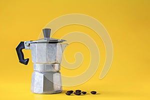 Italian coffee maker and roasted coffee beans  on yellow paper background