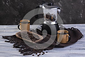 Italian coffee maker and two coffee mugs with roasted coffee beans in wooden container