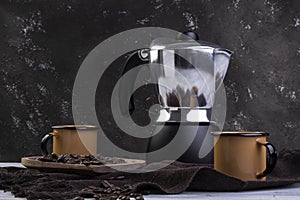 Italian coffee maker and two coffee mugs with roasted coffee beans in wooden container