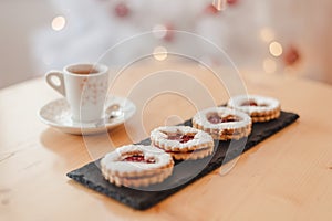 Italian coffee small Cup and cookie on the table near the Christmas tree with golden bokeh