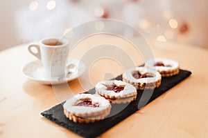 Italian coffee small Cup and cookie on the table near the Christmas tree with golden bokeh