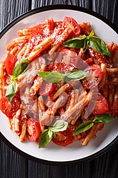 Italian cuisine, classic pasta recipe with tomato sauce, parmesan cheese and basil close-up on a plate. Vertical top view