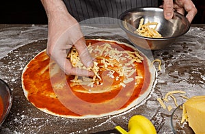 Italian cuisine. Cook adding grated cheese to pizza