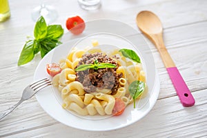 Italian cuisine penne bolognese or Bolognaise sauce noodles pasta meal on a plate on white wooden table