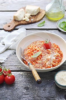 Italian cuisine. Plate of tomato risotto, olive oil, basil and cherry tomatoes