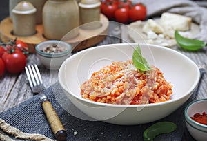 Italian cuisine. Plate of tomato risotto, olive oil, basil and cherry tomatoes