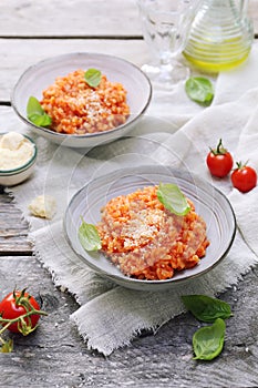 Italian cuisine. Plate of tomato risotto, olive oil, basil and cherry tomatoes, two servings