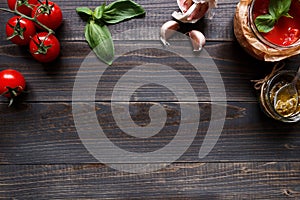 Italian Cuisine. Tomato, basil, garlic and tomato sauce on the dark wooden table top view, with copy space