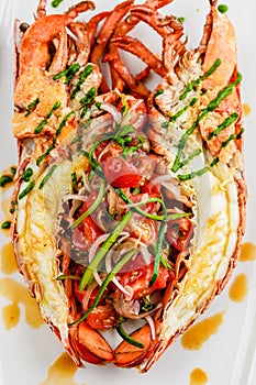 Italian cuisine. Whole lobster baked and sliced in half Served with tomato salad and sauce on white plate