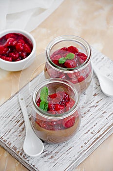 Italian dessert - chocolate panna cotta, mousse, cream or pudding with cherry sauce in a glass jar on a board