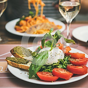 Italian dinner at bistrot with caprese and pasta, square crop photo