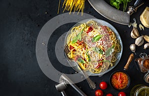 Italian dinner with pasta on ceramic plate with ingredients around on black background. Flat view. Top view