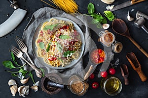 Italian dinner with pasta on ceramic plate with ingredients around on black background. Flat view. Top view