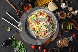 Italian dinner with pasta on ceramic plate with ingredients around on black background. Flat view. Top view