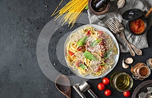 Italian dinner with pasta on ceramic plate with ingredients around on black background. Flat view. Top view