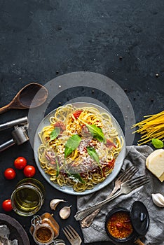 Italian dinner with pasta on ceramic plate with ingredients around on black background. Flat view. Top view