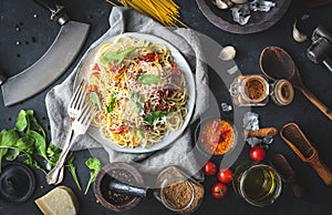 Italian dinner with pasta on ceramic plate with ingredients around on black background. Flat view. Top view