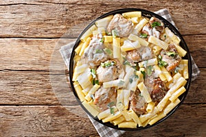 Italian dinner of pasta Tortiglioni with chicken in cheese cream sauce with herbs close up in a dish. Horizontal top view