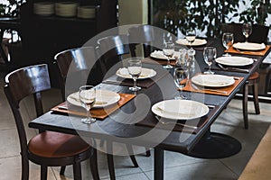 Italian dinner table for eight with cutleries, plates, glasses, napkins and naperies on the table.