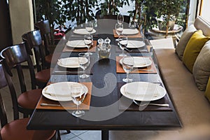 Italian dinner table for eight with cutleries, plates, glasses, napkins and naperies on the table