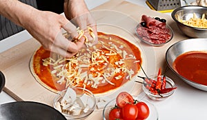 Italian dish. Chef adding grated cheese to pizza
