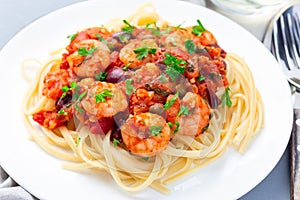 Italian dish shrimp linguine Puttanesca, pasta with shrimps in spicy tomato basil sauce garnished with parsley, horizontal,