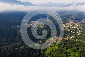 Italian Dolomites mountain valley with town in the country. Aerial beautiful shot above the clouds.