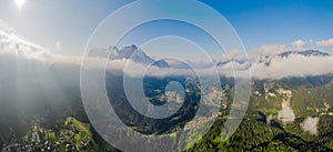 Italian Dolomites mountain valley with town in the country. Aerial beautiful shot above the clouds.