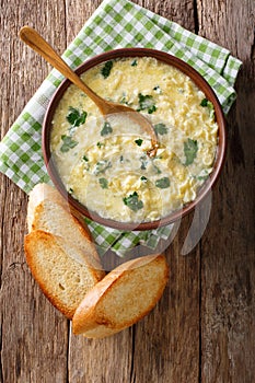 Italian egg soup stracciatella with farfalline pasta and parmesan close-up. Vertical top view