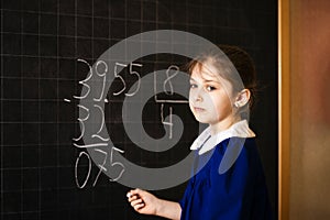 Italian elementary school girl trying to solve a mathematics examples, making a long division at blackboard