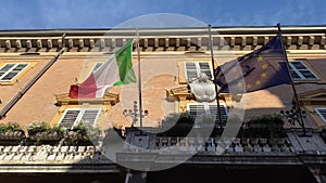 Italian and european flags waving in the wind on the balcony of government building.