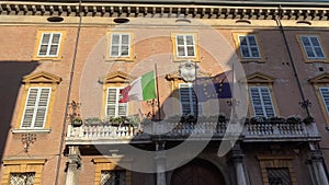 Italian and european flags waving in the wind on the balcony of government building.