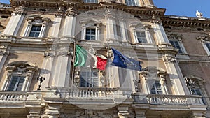 Italian and European flags waving in the wind of the facade of goverment palace
